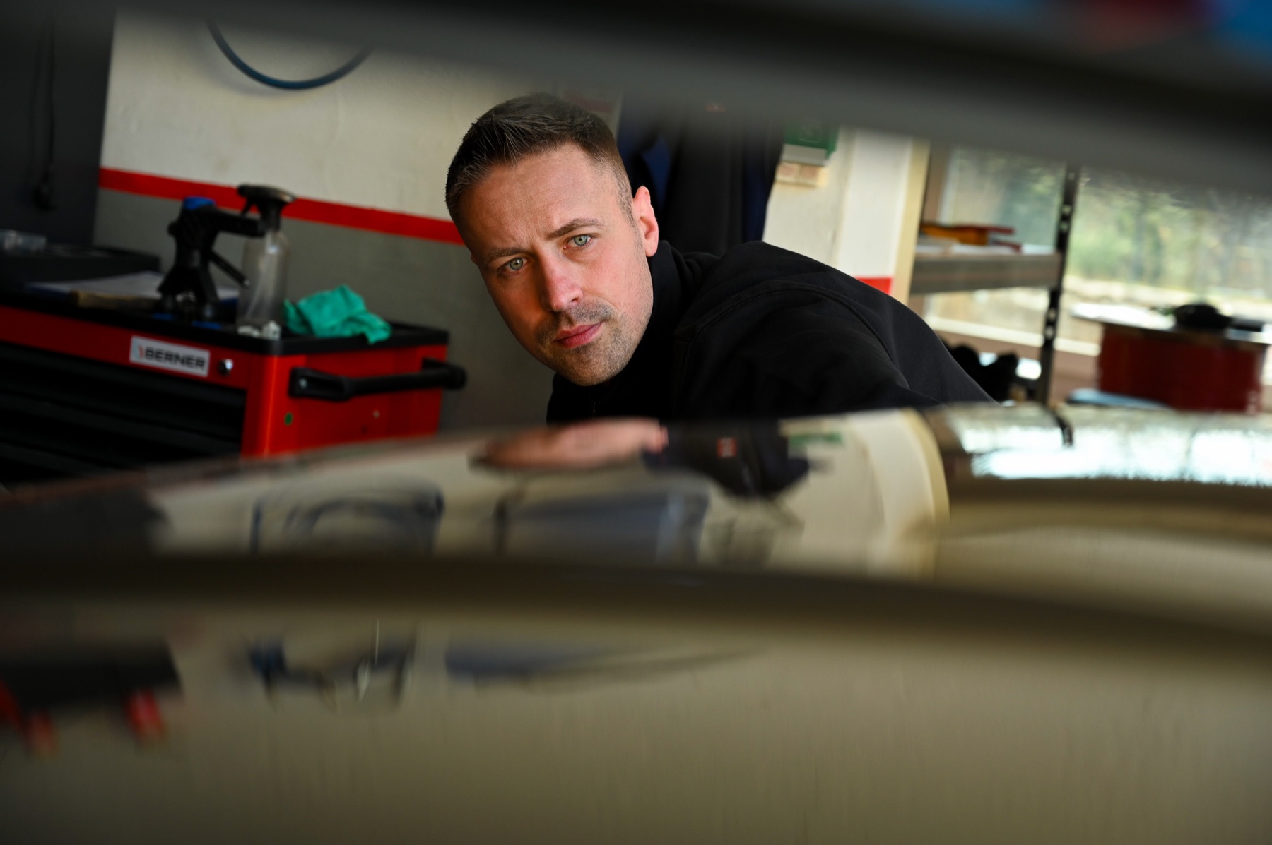 Sebastian Boge prüft die Oberfläche eines Fahrzeugs in seiner Werkstatt.
